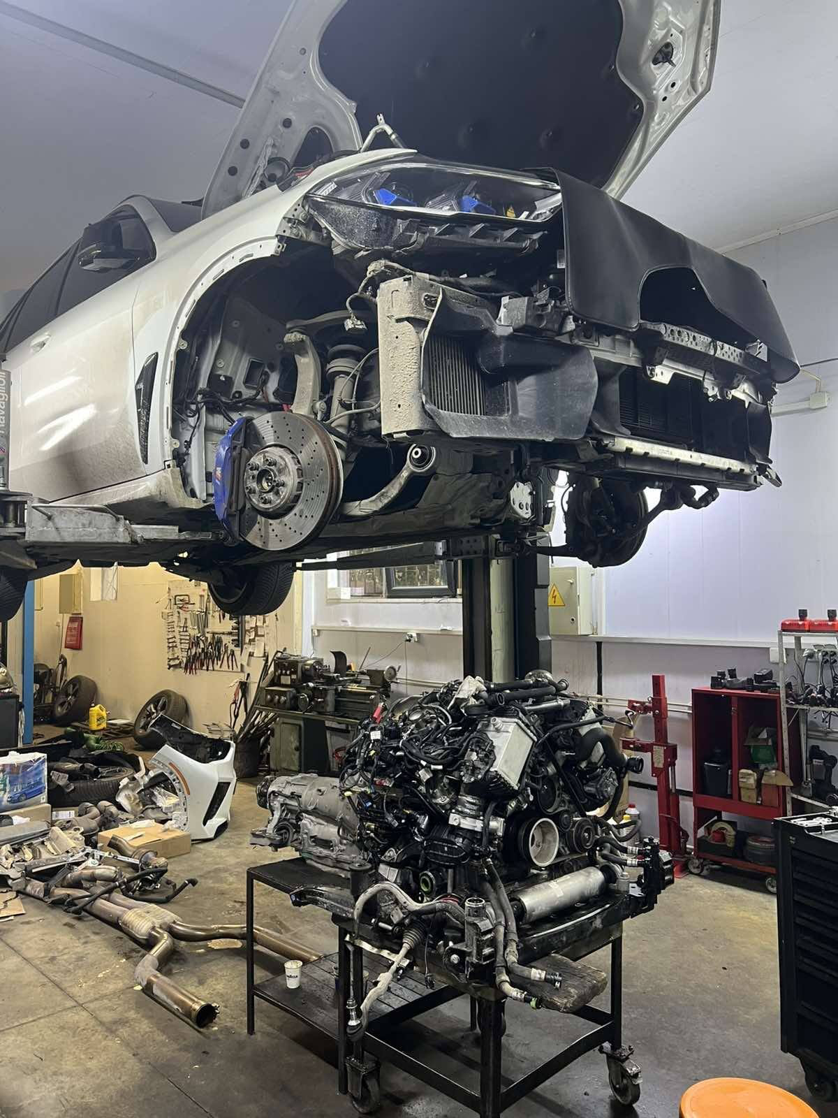Бял BMW на подемник с демонтирана предна част в автосервиз
